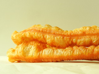 Youtiao, also known deep-fried Chinese doughnut isolated on white newspaper background, normally eaten at breakfast with soy milk in Taiwan. Traditional Chinese snack. Taiwan food culture concept.