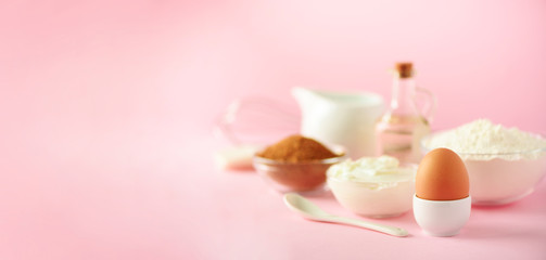 Banner with copy space. Bakery food frame, cooking concept. Different baking ingredients - butter, sugar, flour, milk, eggs, oil, spoon, rolling pin, brush, whisk over pink background.