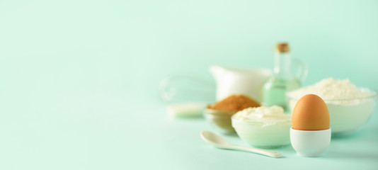 Banner with copy space. Bakery food frame, cooking concept. Different baking ingredients - butter, sugar, flour, milk, eggs, oil, spoon, rolling pin, brush, whisk over blue background.