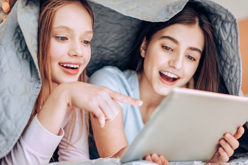 I told you. Happy girl showing her cheerful smile while pointing at screen of tablet