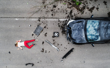 Young injured woman lying on the road after a car accident, unconscious.