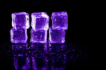 Purple ice cubes reflection on black table background.