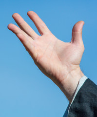 Hand of a man against a blue sky