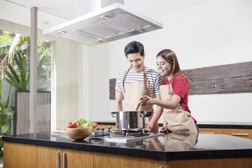 Crédence de cuisine en verre imprimé Cuisinier Cheerful asian couple cooking together