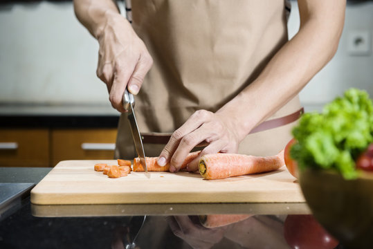 Close up view of man hand slicing carrot on the cutting board