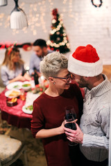 Close up of young in love couple kissing on new years eve. Celebrating with their friends in colorful decorated room.