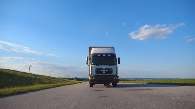 Front view of truck driving on a highway. Lorry rides through the countryside with beautiful landscape at background. Slow motion Close up