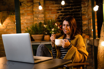 Middle age woman watching her series on laptop while having a snack