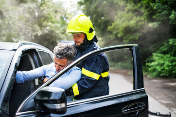 A firefighter getting an unconscious man out of the car after an accident.