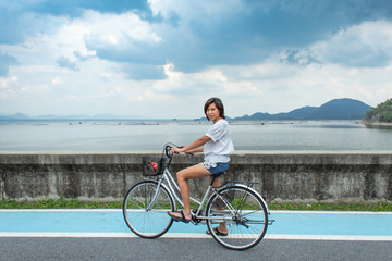 Asian women cycling on the road at Krasiew dam ,Supanburi Thailand.