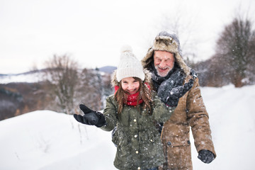 Obraz premium Grandfather and small girl in snow on a winter day.