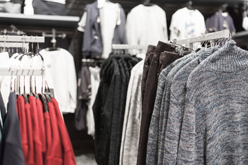 Men's clothes on hangers in the store on a blurred background