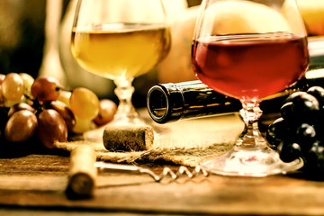 A bottle of wine on a background of glasses and grapes on a wooden table