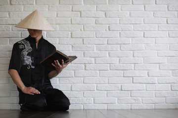 Fototapeta premium Asian young novice on a white brick wall