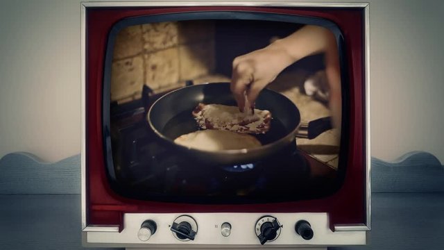 A retro vintage TV showing people frying panzerotti (a savory turnover which resembles a small calzone, both in shape and in the dough used for its preparation) in a pot.
