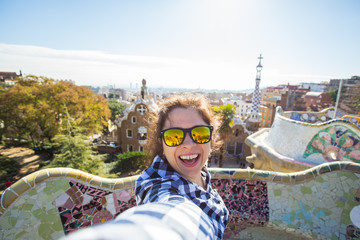 Young happy woman making selfie portrait with smartphone in Park Guell, Barcelona, Spain