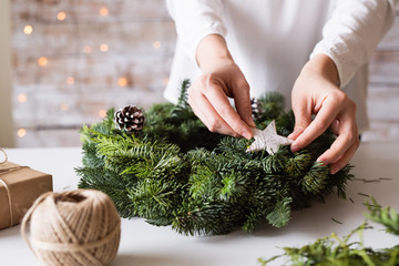Hands of unrecognizable woman decorating christmas wreath.