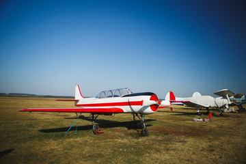 A small white with red plane stands on grass