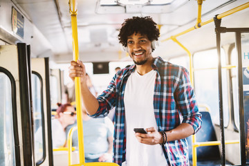 Happy smiled Afro-American standing in a bus and listening to the music over his telephone. © Dusan Petkovic