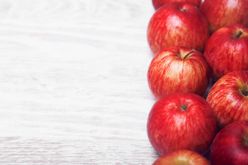 White wooden background and red apples on the right side of the frame, place for the text.