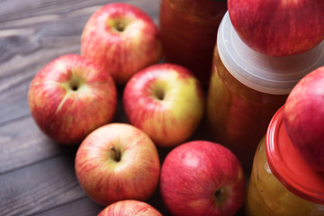 Jars with jam on a background of red apples in a defocus