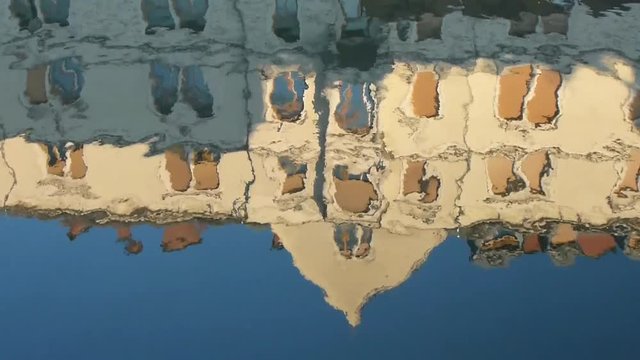 Reflection in the water of an old building. The waves of the bay marvelously distort the picture of the building.