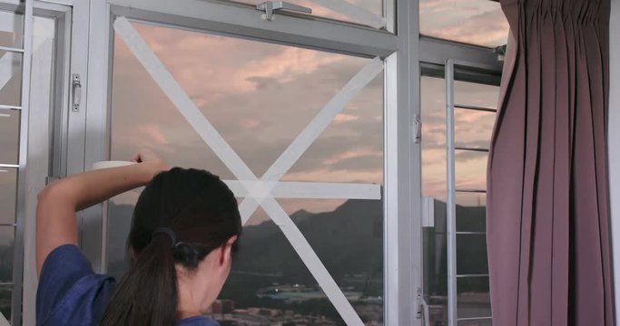 Woman stick tape on window to prevent typhoon