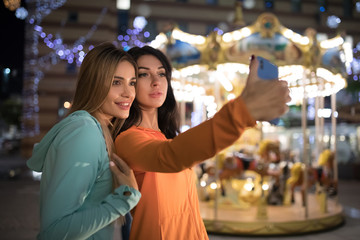 Girls take a selfie, women make mobile photos using smart phone at nigth city