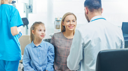 Mother with Sweet Little Girl Visit Friendly Pediatrician. Doctor Talks to Them after Thorough Examination. Brightand Modern Medical Office.