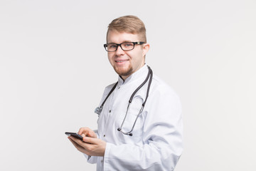 Portrait of male doctor with phone in hands on white background