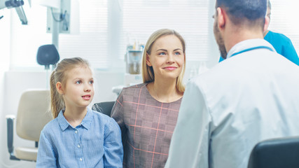 Mother with Sweet Little Girl Visit Friendly Pediatrician. Doctor Talks to Them after Thorough Examination. Brightand Modern Medical Office.