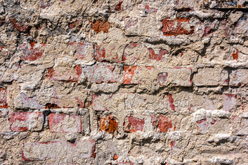An old brick wall with concrete coating adhered