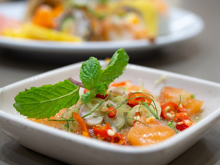 Spicy Salmon salad with Thai herbs in special sauce in a white plate.Salmon topped with coriander. In Japanese Restaurant.