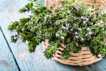 Fresh thyme in a basket over blue rustic wooden background with copyspace.