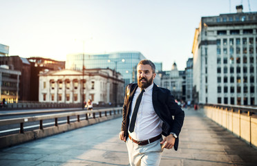 Hipster businessman running on the street in the city.