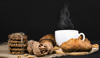 Fresh croissants, coffee,  nuts on dark chalkboard background.