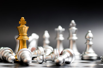 Gold king chess piece face with another silver team and have pawn lay down on black background (Concept for company strategy, business victory or decision)