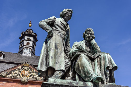 Germany, Hanau: National memorial statue of famous Grimm Brothers in the city center of the German town with town hall and blue sky in background - concept culture fairy tales art travel history