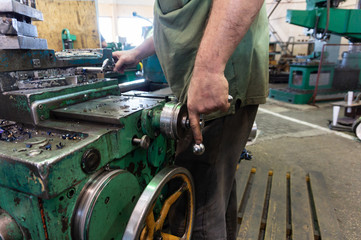 Worker, a man processes metal products on a machine. Turning work in production.