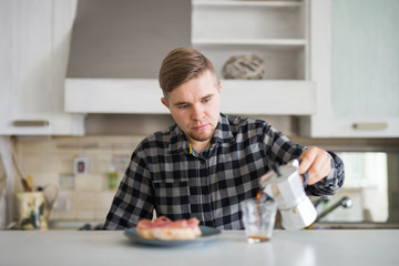Morning, drink and people concept - Portrait of handsome man pouring coffee in a coffee mug at the kitchen