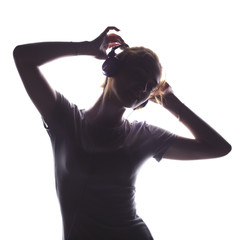 silhouette of a girl listening to music in headphones, young woman relaxing on a white isolated background