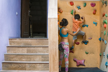 The boy climbs on the children's climbing wall.