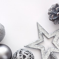 Square photo of silver Christmas balls, pinecone and star on a white background. Copy space