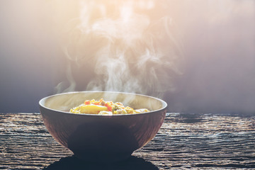 Soft focus Bowl of hot food with steam on dark background.