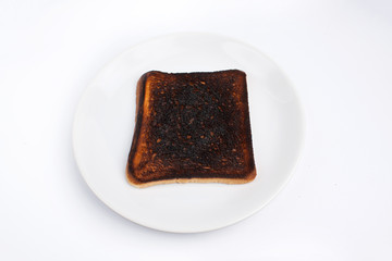 Burned toast lies on a white plate on a white background