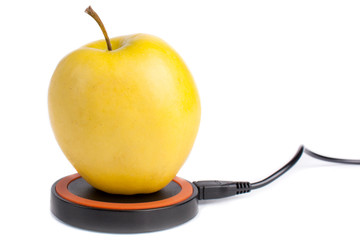 Yellow apple lies on a platform for wireless charging on an isolated white background