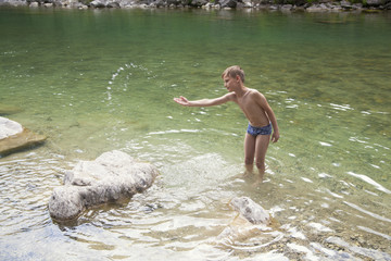 Boy standing in the river and splashing around