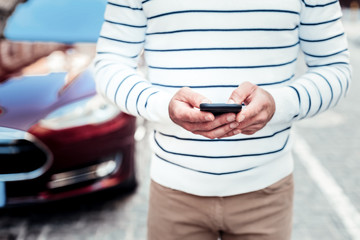Modern technologies. Close up of male person that holding his telephone and bowing head while standing on the foreground