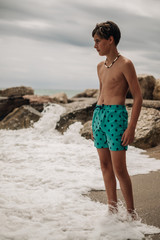 Boy standing on the beach while waves hitting his legs