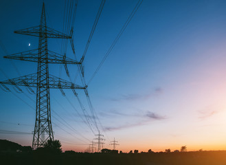 Fototapeta premium słupy elektryczne o zachodzie słońca transportujące czystą energię odnawialną